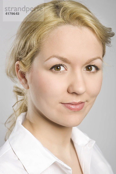 Portrait einer jungen blonden Frau in weißer Bluse  mit freundlichem Blick
