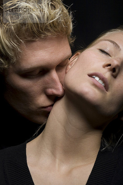 Mann küsst den Hals einer Frau