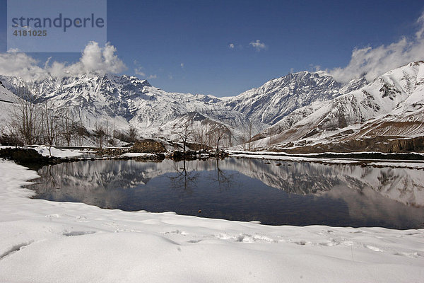 Schneebedeckte Berge spiegeln sich im Wasser eines kleinen Sees beim Bergdorf Jharkot  Nepal  Asien