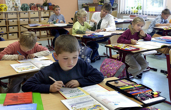 Grundschulschueler schreiben im Klassenzimmer