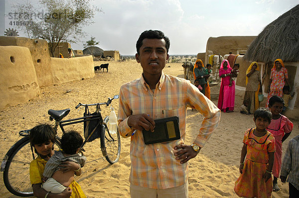 Junger Mann mit Radio und Fahrrad in einem Dorf mit vielen Menschen  Wüste Thar bei Jaisalmer  Rajasthan  Indien  Asien
