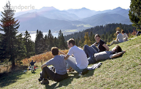 Tegernsee  DEU  30.10.2005 - Menschen sitzen auf der Wiese am Neureuthaus (1.263 m) auf dem Wanderweg zwischen Schliersee und Tegernsee. Im Hintergrund ist der Tegernsee zu sehen.