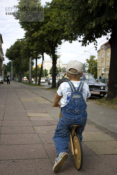 Eine Strassenidylle in Potsdam  Deutschland mit kleinem Jungen der ein Laufrad fährt