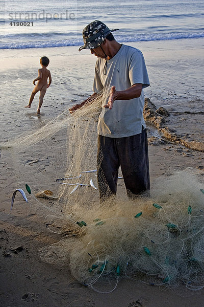 Ein Fischer entleert seinen Fang am Strand von Miu Ne  Vietnam  Asien