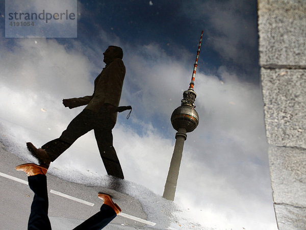 Fußgänger und Fernsehturm spiegeln sich in Pfütze  Alexanderplatz  Berlin  Deutschland