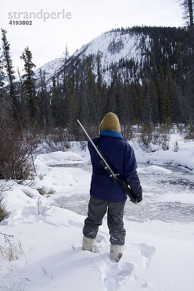 Jäger sucht Wild  Spuren  Bach  Gewehr  Yukon Territory  Kanada  Nordamerika