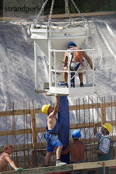 Bauarbeiter mit Betonbehälter auf einer Großbaustelle