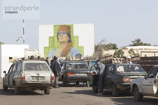 Autos an der Grenze Tunesien-Lybien mit Portraet von Staatschef Kadhdhafi Gaddafi auf einer Plakatwand  Lybien