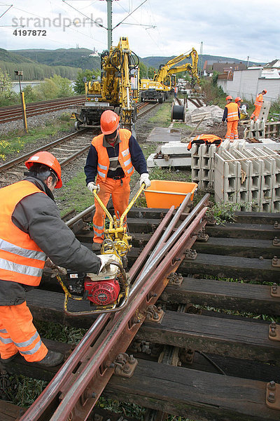 Arbeiter wechseln mit einem Gleisbauzug die Bahngleise und Schellen aus.