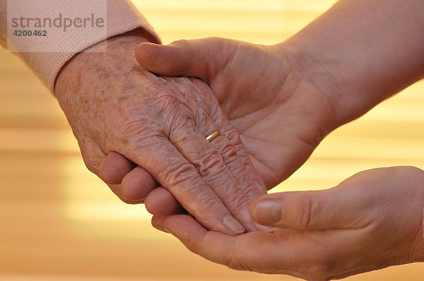 Frau hält Hand von Seniorin