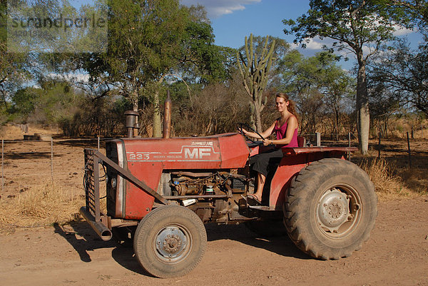Junge Frau auf antiquiertem Traktor in Südamerika