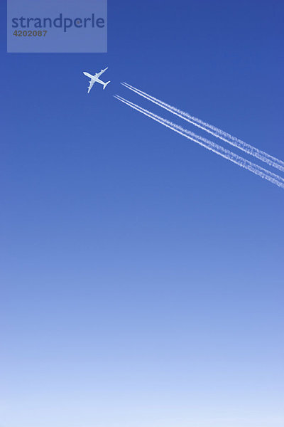 Ein einzelnes Passagierflugzeug in eisiger Höhe mit Kondensstreifen im blauen Himmel