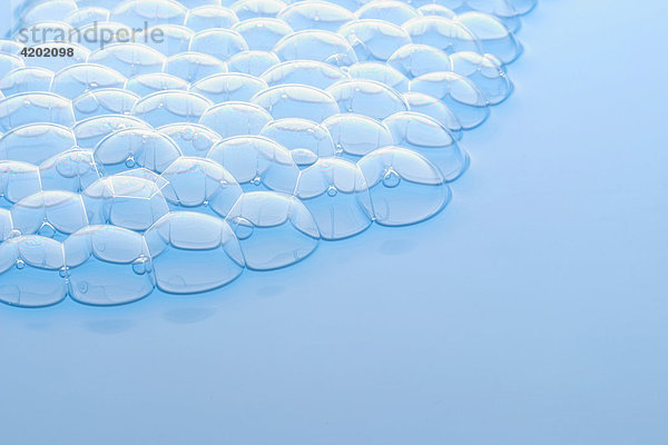 Many small soap bubbles swimmming on soft blue water surface