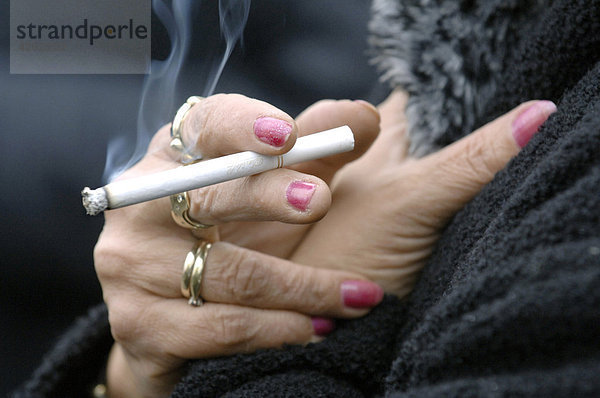 Rauchen - Frau raucht eine Zigarette  Hände mit Ringen