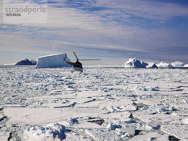 Hubschrauber fliegt zu den Eisbergen vor Franklin Island  Antarktis