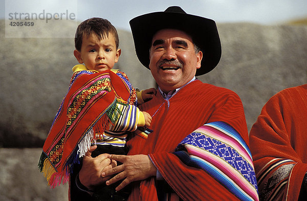 Mann mit Kind auf dem Arm. Vater und Sohn in landestypischer Kleidung   Südamerika  Peru   Anden