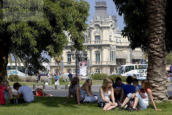 Touristen sitzen auf Grünfläche an der Rambla  Zollhaus  Barcelona  Katalonien  Spanien