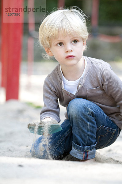 Blonder Junge spielt auf dem Spielplatz