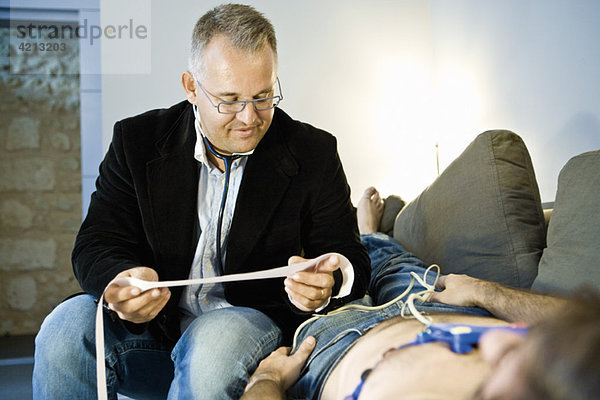 Arzt  der ein tragbares EKG (Elektrokardiogramm) am Patienten zu Hause durchführt.