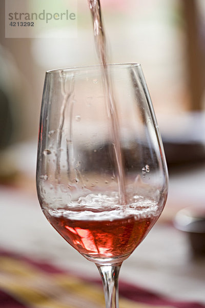 Gießen eines Glases Rosenwein