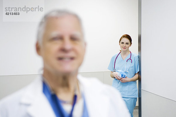 Krankenschwester lehnt sich an die Wand und schaut mit Bewunderung auf den Arzt.