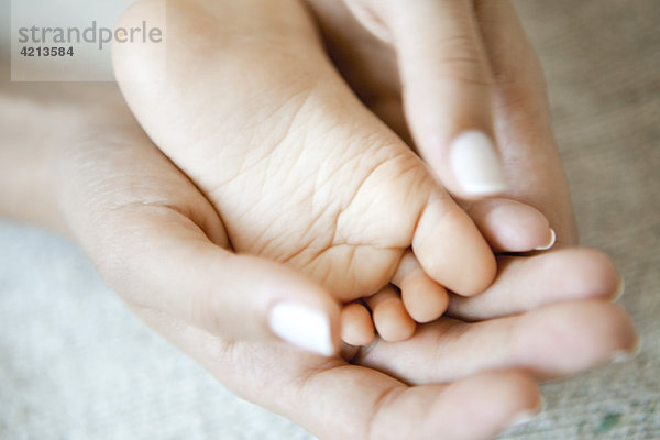 Frauenhände halten Babyfuß