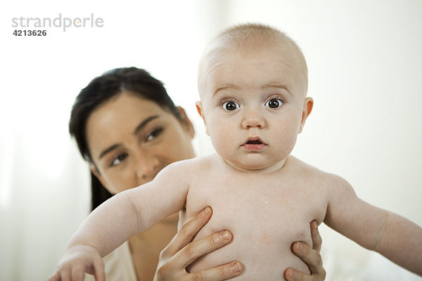 Mutter hält Baby mit überraschtem Gesichtsausdruck  Portrait