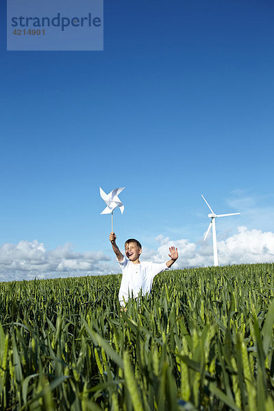 Junge läuft im Feld mit Windkraftanlage