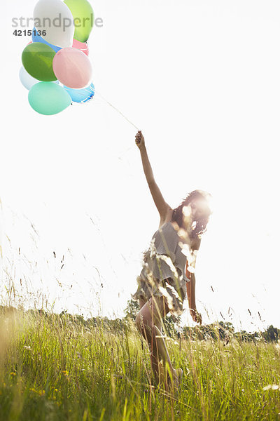 Frau mit Luftballons im Feld unterwegs