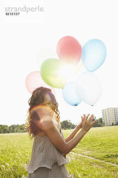 Frau mit Luftballons auf der Wiese