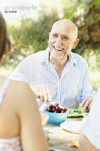 Lächelnder älterer Mann am Picknicktisch