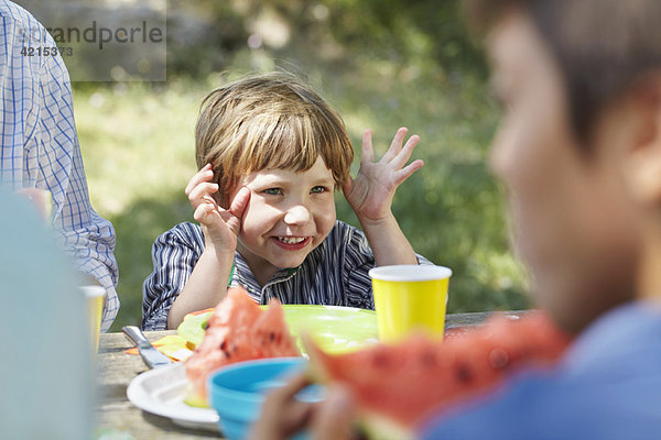 Gestikulierender kleiner Junge beim Picknick