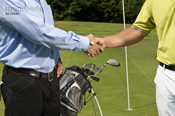 Golfer und Caddy beim Händeschütteln
