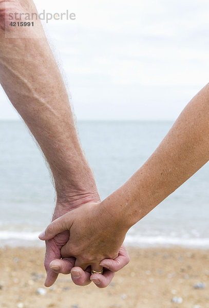Senioren halten Hände am Strand