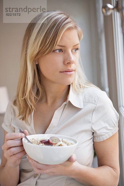 Frau beim Frühstücken am Fenster