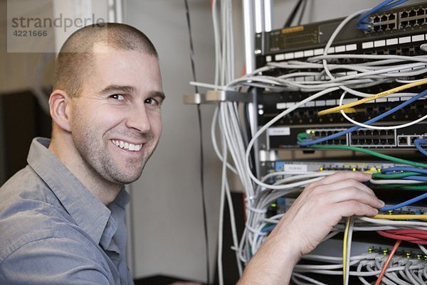 Glücklicher Mann beim Reparieren von Netzwerkkabeln