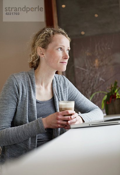 Frau im Kaffeehaus mit Blick aus dem Fenster