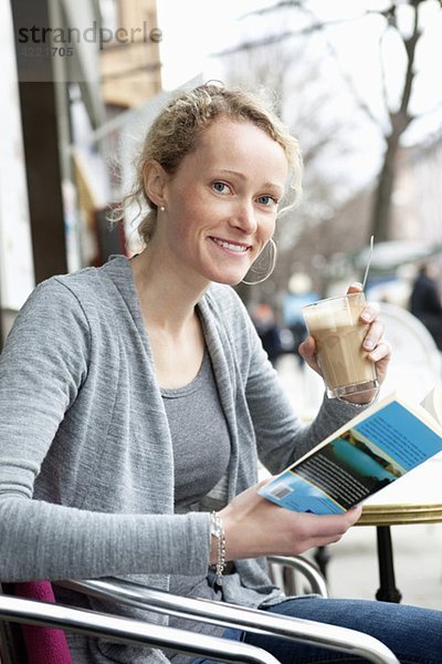 Frau liest Buch im Kaffeehaus