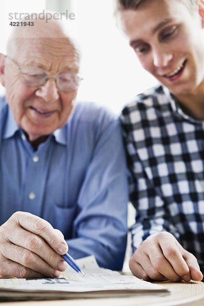 Kerl und älterer Mann lösen Kreuzworträtsel