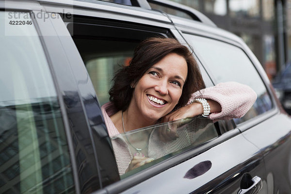 Frau  die sich aus dem Autofenster lehnt.