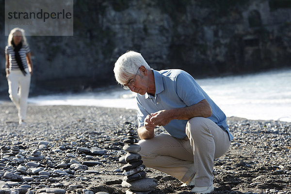 Senior stapelt Steine am Strand  Italien  Sori