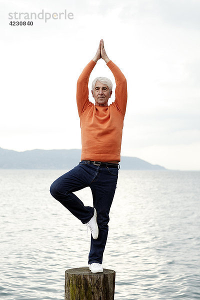 Senior macht eine Yogaübung am Wasser  Italien  Gargnano  Gardasee