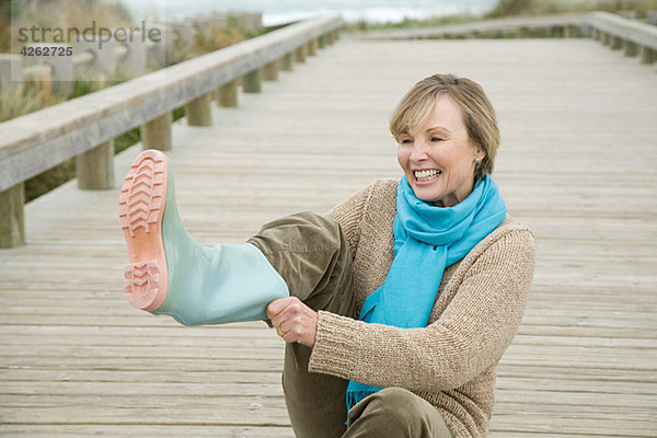 Frau zieht Gummistiefel an