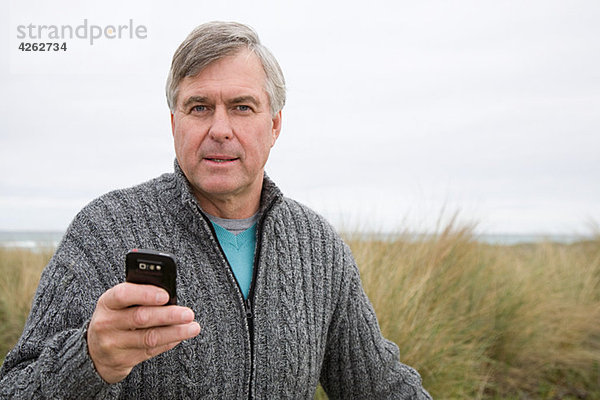 Mann an der Küste mit Smartphone