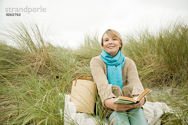 Frau mit einem Buch über eine Düne