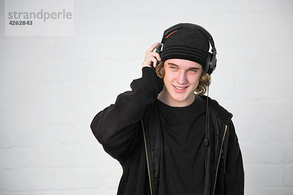 Porträt eines Teenagers  der Musik über Kopfhörer hört.