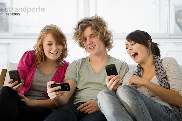 Drei Teenager-Freunde schauen auf Smartphones