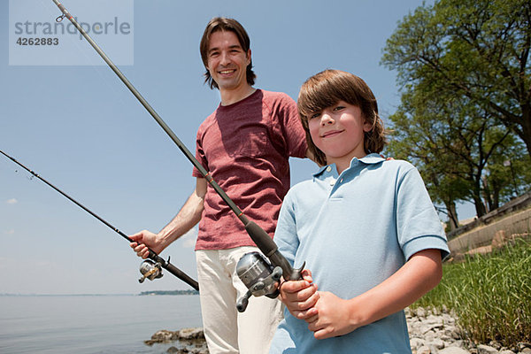 Vater und Sohn am Strand mit Angelruten