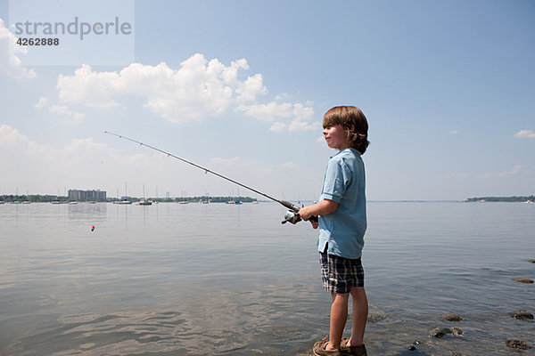 Kleiner Junge beim Fischen am Strand