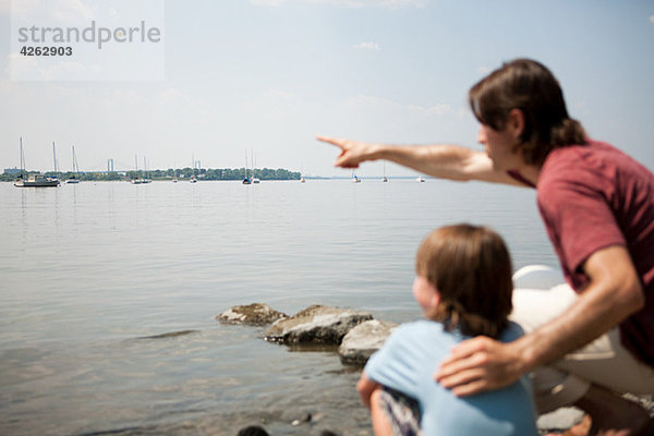 Vater und Sohn am Strand  Vater zeigt über den Hafen